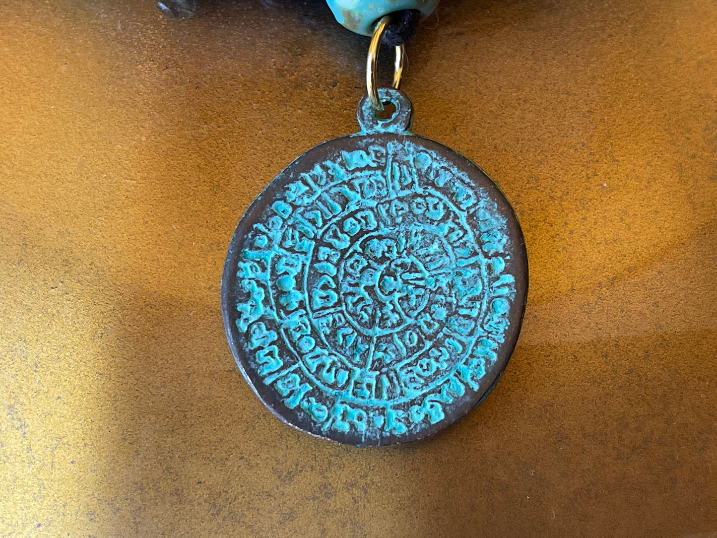 Phaistos Disk pendant charm – cast bronze with a green patina – made in Mykonos Greece – detailed replica of Archaeological artifact