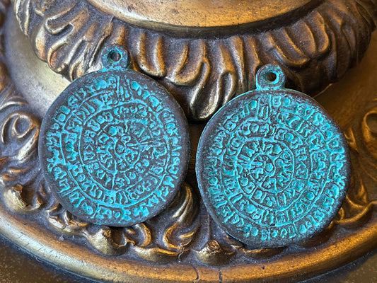 Phaistos Disk pendant charm – cast bronze with a green patina – made in Mykonos Greece – detailed replica of Archaeological artifact